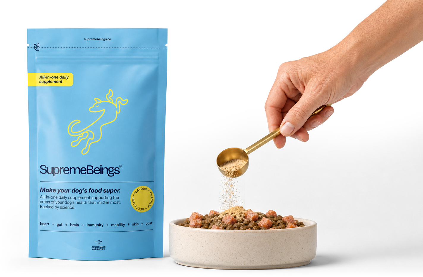 Supreme Beings pouch beside a bowl of food, with a scoop of supplement powder being added